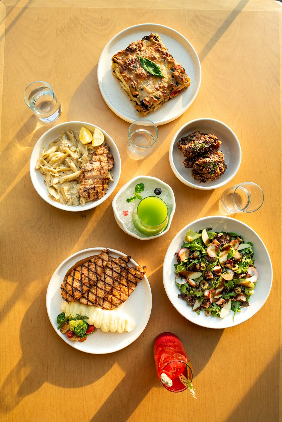 Several plated meals and drinks arranged on a wooden table.